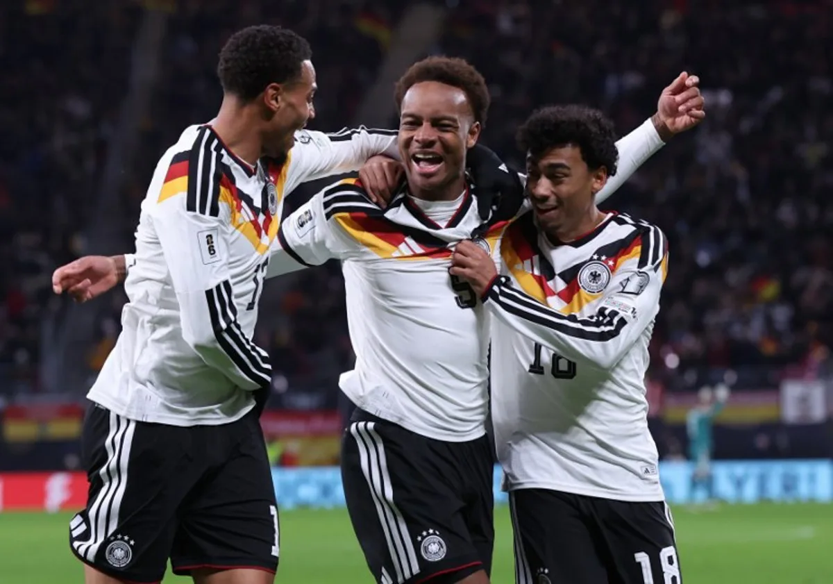 Germany's midfielder #09 Assan Ouedraogo (C) celebrates with Germany's midfielder #13 Felix Nmecha (L) and Germany's defender #18 Nathaniel Brown scoring his team's sixth goal during the FIFA World Cup 2026 European qualification Group A football match between Germany and Slovakia, at the Red Bull Arena in Leipzig, eastern Germany on November 17, 2025. Ronny HARTMANN / AFP