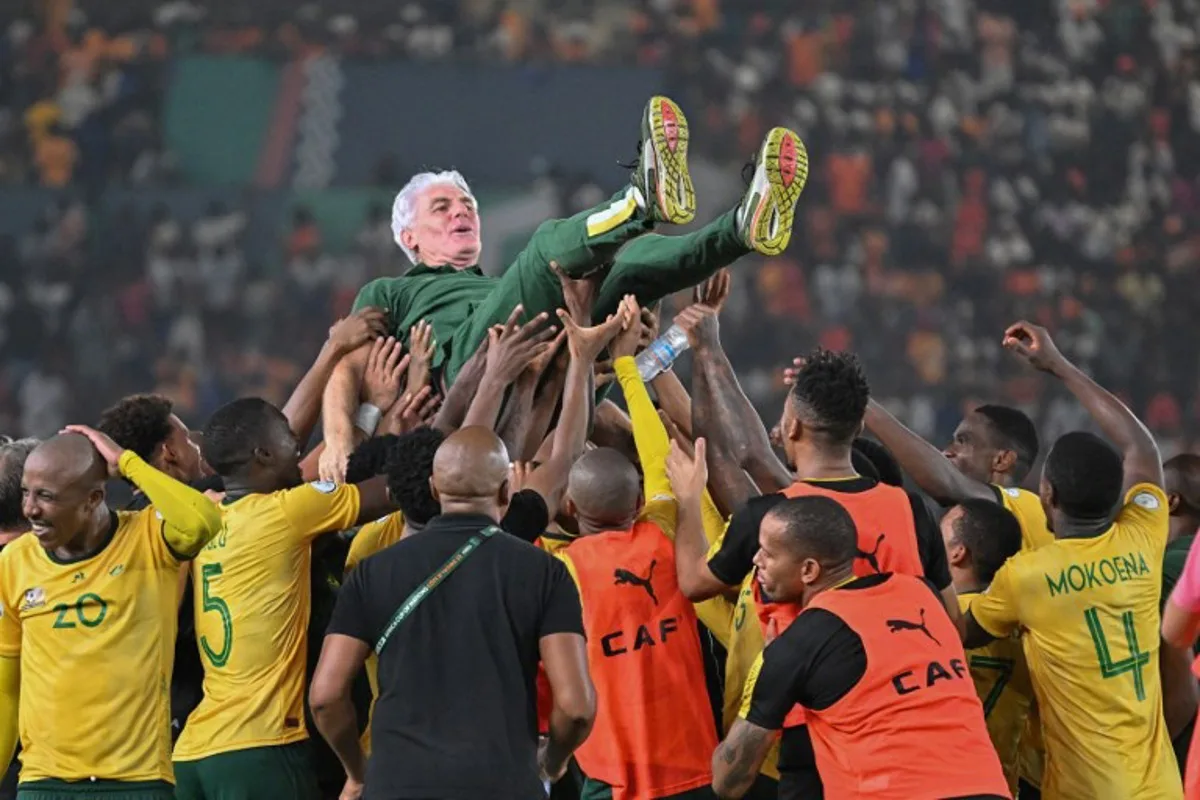 South Africa's head coach Hugo Broos is lifted in the air by South African players after they won the Africa Cup of Nations (CAN) 2024 third place play-off football match between South Africa and Democratic Republic of Congo at Felix Houphouet-Boigny Stadium in Abidjan on February 10, 2024.  Sia KAMBOU / AFP