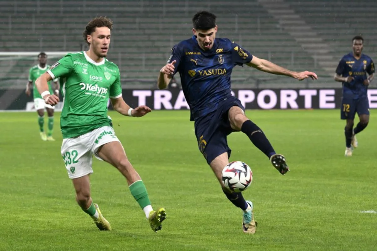 Reims' Belgian defender #25 Thibault De Smet controls the ball next to Saint Etienne's Belgian forward #32 Lucas Stassin during the French L1 football match between AS Saint-Etienne and Stade de Reims at the Geoffroy-Guichard Stadium in Saint-Etienne, central France on January 4, 2025.  JEAN-PHILIPPE KSIAZEK / AFP