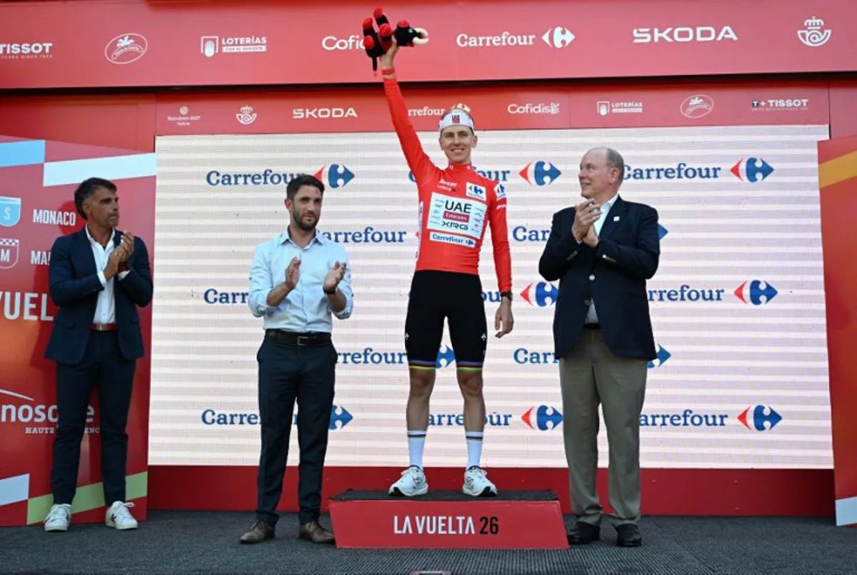 UAE Team Emirates - XRG team's Slovenian rider Tadej Pogacar celebrates on the podium wearing the overall leader's red jersey flanked by (from R) Prince's Albert II of Monaco, Manosque's mayor Camille Galtier and Spanish former Tour de France winner Oscar Pereiro after the second stage of the Vuelta a Espana 2026, a 214,3 km race between Monaco and Manosque on August 23, 2026.  Miguel MEDINA / AFP