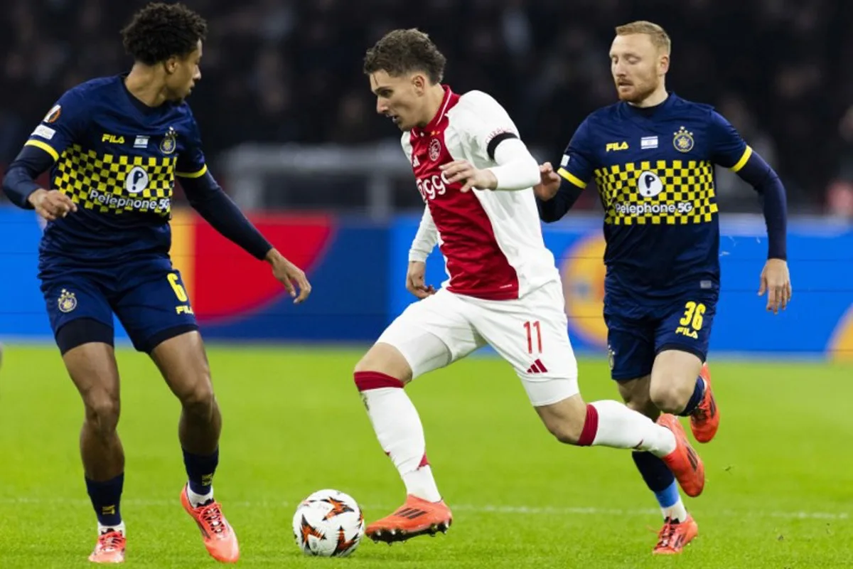 Ajax's Belgian forward #11 Mika Godts (C) runs with the ball past Maccabi Tel Aviv's Dutch defender #06 Tyrese Asante and Maccabi Tel Aviv's Israeli midfielder #36 Ido Shahar  during the UEFA Europa League, League phase - Matchday 4, football match between Ajax Amsterdam and Maccabi Tel Aviv at the Johan-Cruijff stadium, in Amsterdam on November 7, 2024.  Robin van Lonkhuijsen / ANP / AFP