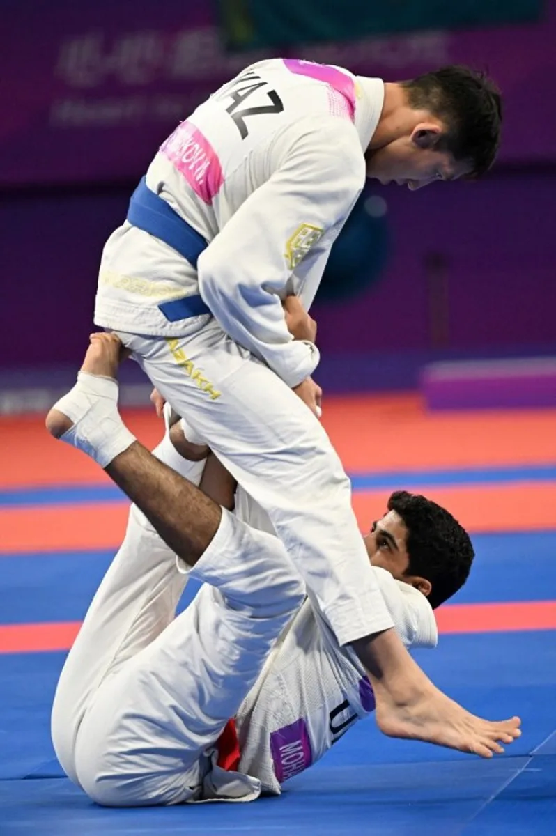 Kazakhstan's Nurzhan Batyrbekov (top) competes against United Arab Emirates' Mohamed Alsuwaidi (bottom)at the jiu jitsu men's 69kg final event during the Hangzhou 2022 Asian Games in Hangzhou, in China's eastern Zhejiang province on October 5, 2023.  Adek BERRY / AFP