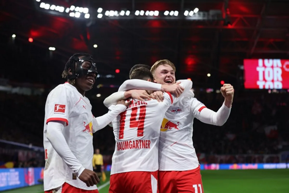 Leipzig's Danish forward #11 Conrad Harder (R) celebrates scoring the 1-0 opening goal with Leipzig's Ivorian forward #49 Yan Diomande (L) and Leipzig's Austrian midfielder #14 Christoph Baumgartner (C) during the German first division Bundesliga football match between RB Leipzig and Eintracht Frankfurt in Leipzig, eastern Germany, on December 6, 2025. Ronny HARTMANN / AFP