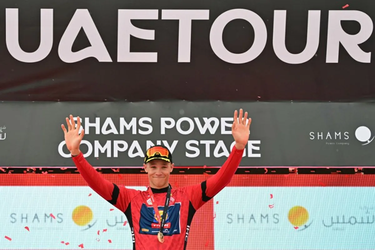 Lidl-Trek team's Italian rider Jonathan Milan celebrates on the podium after winning the first stage of the UAE Tour cycling race from Shams Solar Power Station Madinat Zayed to Liwa Palace in Abu Dhabi on February 17, 2025.  Giuseppe CACACE / AFP