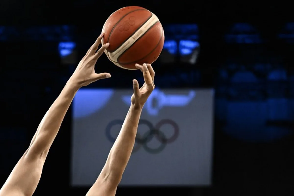 A player reaches for the ball, as Olympic rings are seen in the backgroud in the men's quarterfinal basketball match between Serbia and Australia during the Paris 2024 Olympic Games at the Bercy  Arena in Paris on August 6, 2024.  Aris MESSINIS / AFP