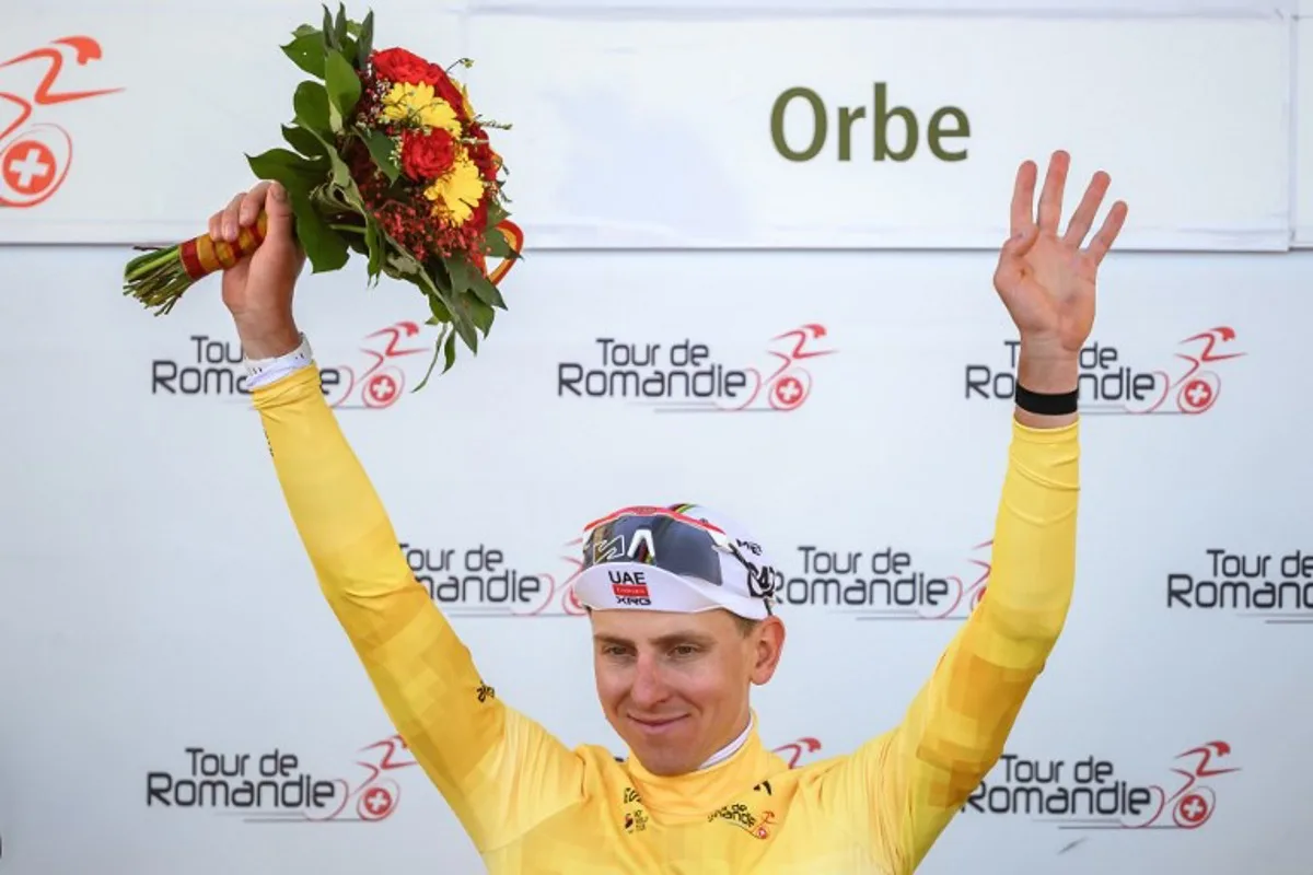 UAE Team Emirates-XRG's Slovenian rider Tadej Pogacar wearing the overall leader's yellow jersey raises his arms during the podium ceremony of the third stage of the Tour of Romandie UCI cycling World tour, a 176.6 km loop departing and arriving in Orbe, Switzerland, on May, 1, 2026.  Fabrice COFFRINI / AFP