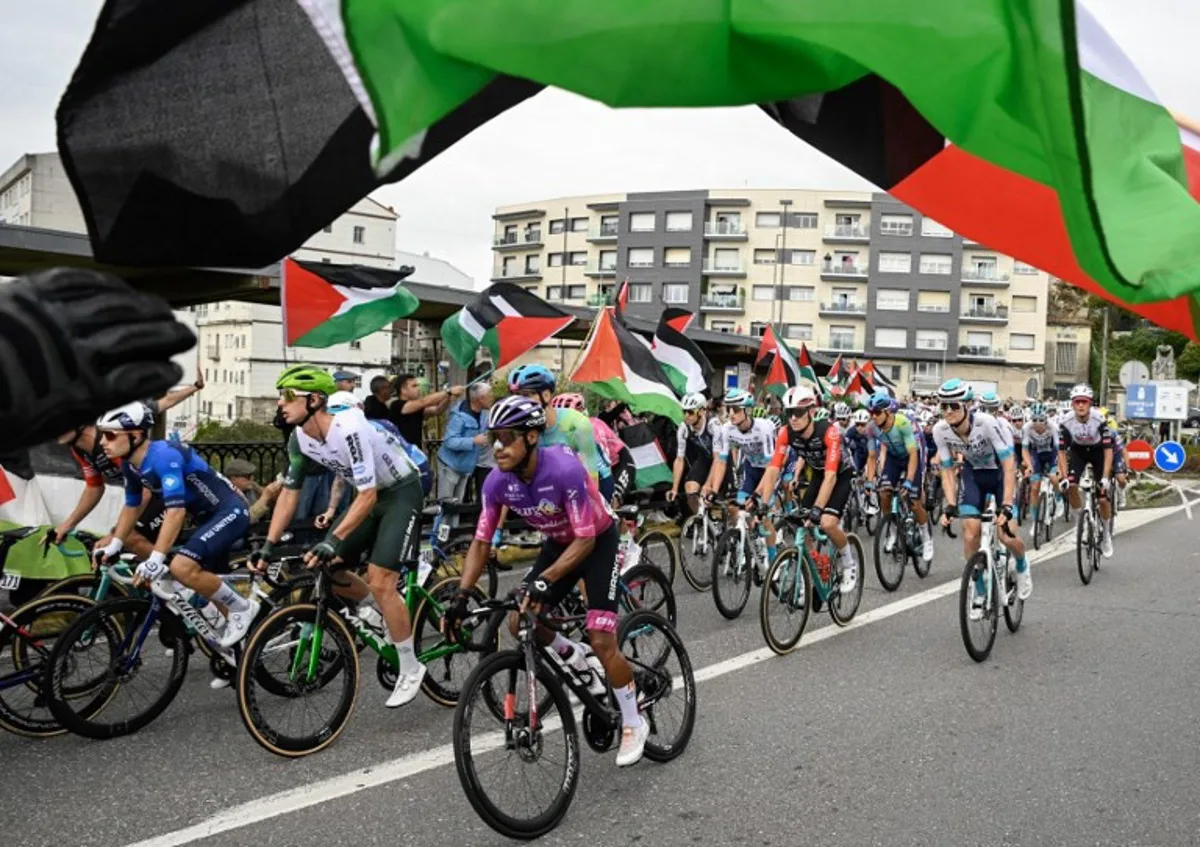 Pro-Palestinian protesters wave flags and shout as the peloton rides by in Poio at the start of the 16th stage of the Vuelta a Espana, a 172 km race between Poio and Castro de Herville, on September 9, 2025. Miguel RIOPA / AFP