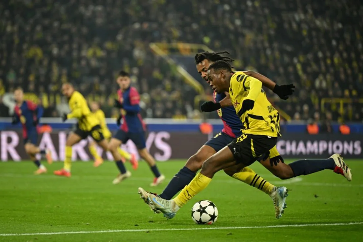 Barcelona's French defender #23 Jules Kounde (L) and Borussia Dortmund's Belgian forward #16 Julien Duranville vie for the ball during the UEFA Champions League football match between Borussia Dortmund and FC Barcelona in Dortmund, western Germany on December 11, 2024.  INA FASSBENDER / AFP