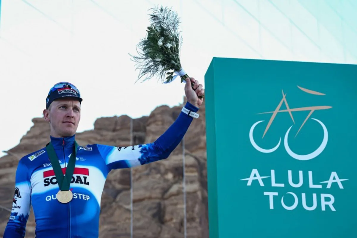 Belgium's Tim Merlier (L) of Soudal Quick-Step celebrates in the podium after winning the fourth stage of AlUla Tour cycling race between Hegra and Maraya near Al-Ula on February 2, 2024.  Anne-Christine POUJOULAT / AFP