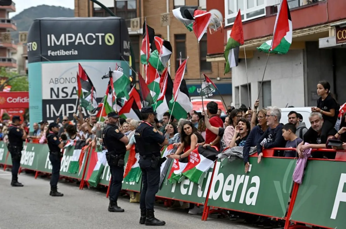 Police officers stand as Pro-Palestinian demonstrators wave Palestinian flags at the finish line of the 12th stage of the Vuelta a Espana, a 144,9 km race between Laredo and Corrales de Buelna, on September 4, 2025. ANDER GILLENEA / AFP