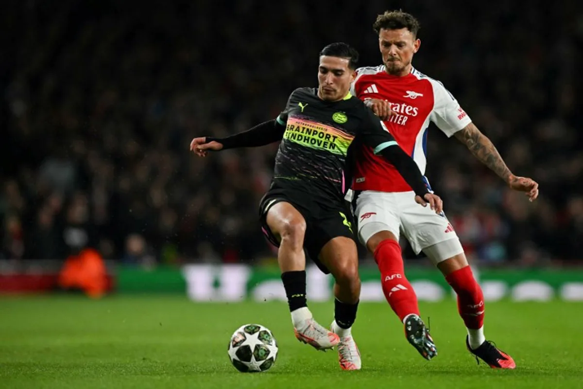 PSV Eindhoven's Dutch forward #21 Couhaib Driouech (L) fights for the ball with Arsenal's English defender #04 Ben White during the last 16 second leg UEFA Champions League football match between Arsenal and PSV Eindhoven at the Emirates Stadium in north London on March 12, 2025.  Glyn KIRK / AFP