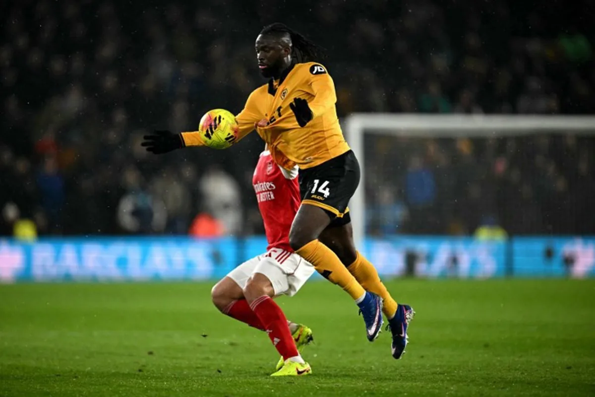 Arsenal's French defender #02 William Saliba pulls the shirt of Wolverhampton Wanderers' Nigerian striker #14 Tolu Arokodare during the English Premier League football match between Wolverhampton Wanderers and Arsenal at the Molineux stadium in Wolverhampton, central England on February 18, 2026. Paul ELLIS / AFP