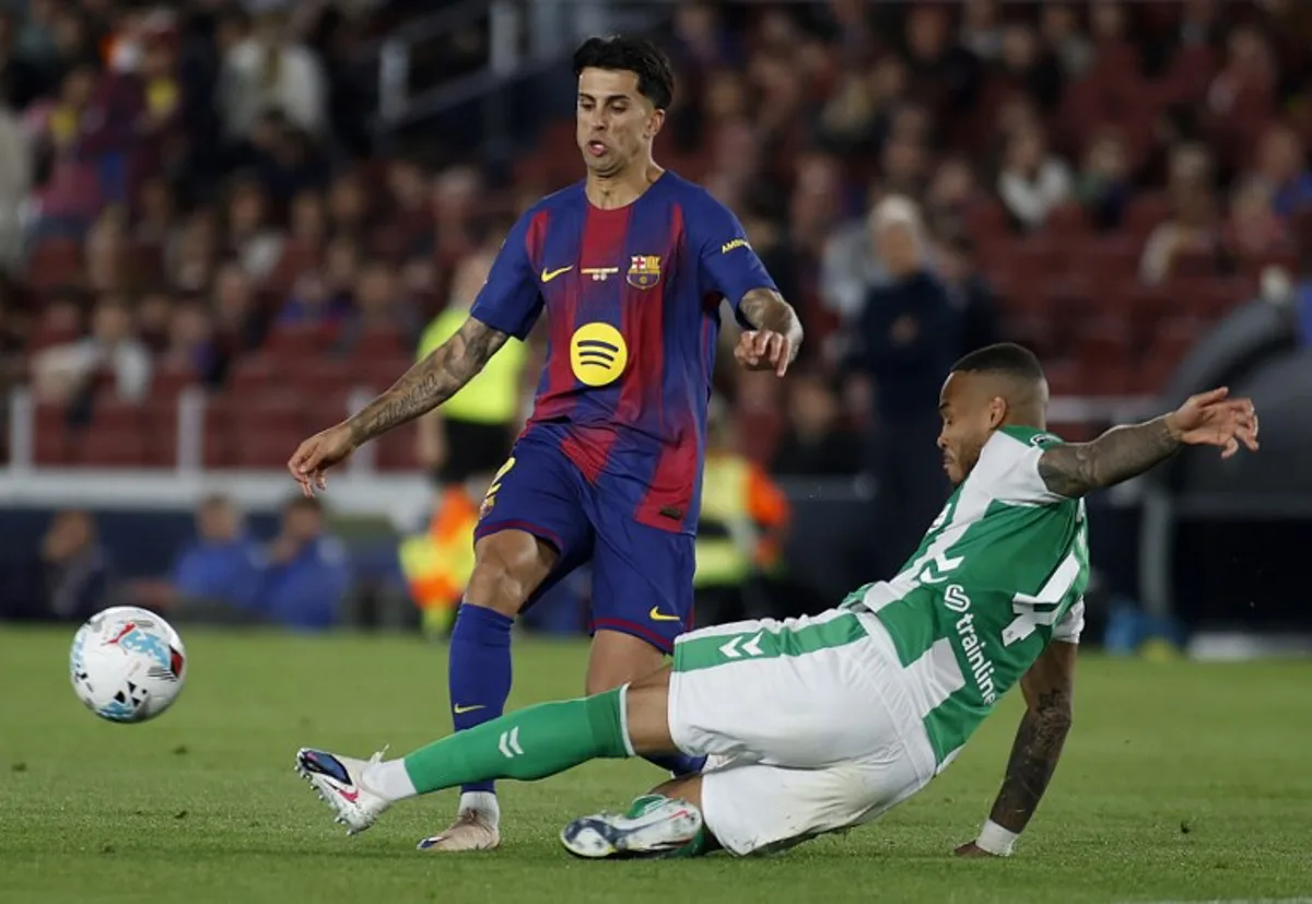 Barcelona's Portuguese defender #02 Joao Cancelo (L) is tackled by Real Betis' Brazilian defender #04 Natan Bernardo de Souza during the Spanish league football match between FC Barcelona and Real Betis at the Camp Nou Stadium in Barcelona on May 17, 2026. JAIME REINA / AFP