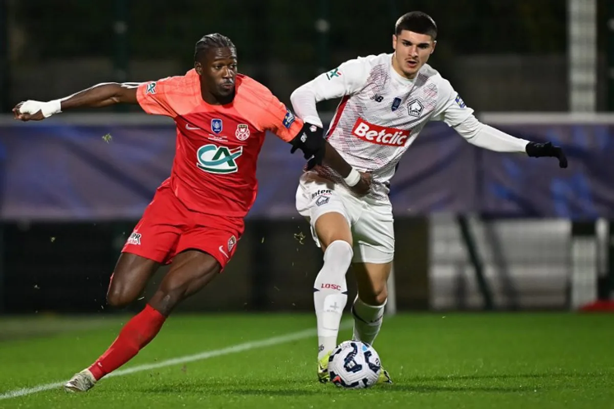 Rouen's French defender Dany Goprou (L) fights for the ball with Lille's Belgian forward #19 Matias Fernandez-Pardo during the French Cup football match between FC Rouen and LOSC Lille, at the Robert Diochon Stadium in Petit-Quevilly, north-western France, on December 20, 2024.  Lou BENOIST / AFP