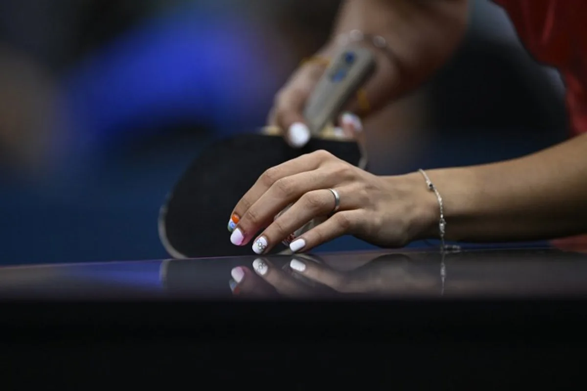 A detailed view of India's Manika Batra's nails painted with the Indian flag and Olympic Rings as she prepares to serve the ball during her women's table tennis singles match in the team quarter-finals between India and Germany at the Paris 2024 Olympic Games at the South Paris Arena in Paris on August 7, 2024.  WANG Zhao / AFP