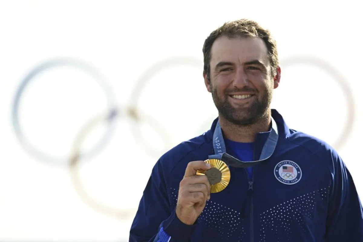 Gold medallist US' Scottie Scheffler poses for pictures on the podium after round 4 of the men's golf individual stroke play of the Paris 2024 Olympic Games at Le Golf National in Guyancourt, south-west of Paris on August 4, 2024.   John MACDOUGALL / AFP