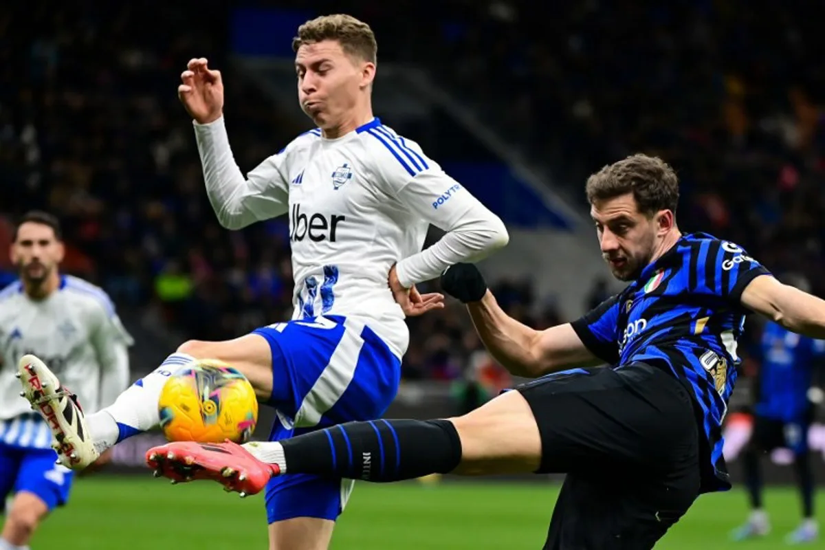 Inter Milan's Brazilian defender #30 Carlos Augusto (R) shoots the ball past Como's Belgian defender #77 Ignace Van der Brempt during the Italian Serie A football match between Inter Milan and Como at the San Siro Stadium in Milan on December 23, 2024.   Piero CRUCIATTI / AFP