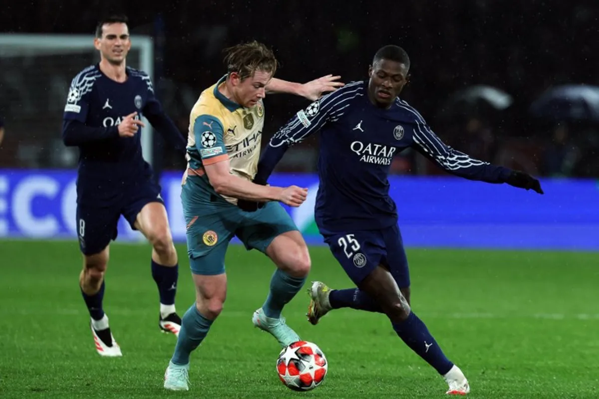 Manchester City's Belgian midfielder #17 Kevin De Bruyne and Paris Saint-Germain's Portuguese defender #25 Nuno Mendes (R) fight for the ball during the UEFA Champions League, league phase football match between Paris Saint-Germain and Manchester City at the Parc des Princes Stadium in Paris on January 22, 2025.   Thomas SAMSON / AFP