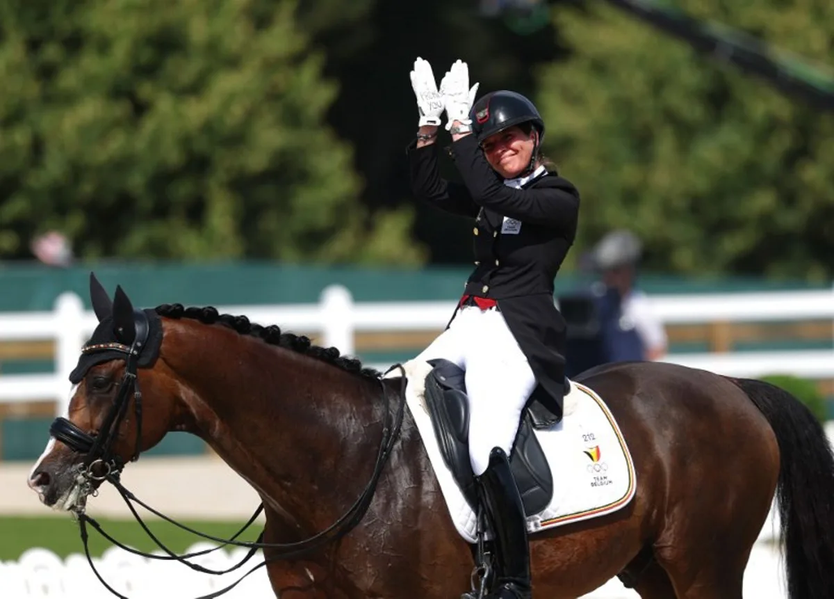 Belgium's Larissa Pauluis with horse Flambeau waves after competing in the equestrian's dressage individual grand prix day 1 during the Paris 2024 Olympic Games at the Chateau de Versailles, in Versailles, in the western outskirts of Paris, on July 30, 2024.  Pierre-Philippe MARCOU / AFP