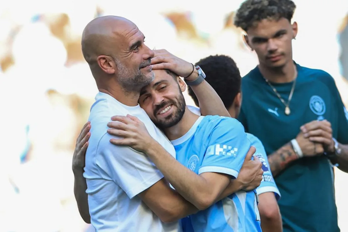 Manchester City's Spanish manager Pep Guardiola (L) embraces Manchester City's Portuguese midfielder #20 Bernardo Silva (C) during ceremonies following the English Premier League football match between Manchester City and Aston Villa at the Etihad Stadium in Manchester, north west England, on May 24, 2026. Darren Staples / AFP