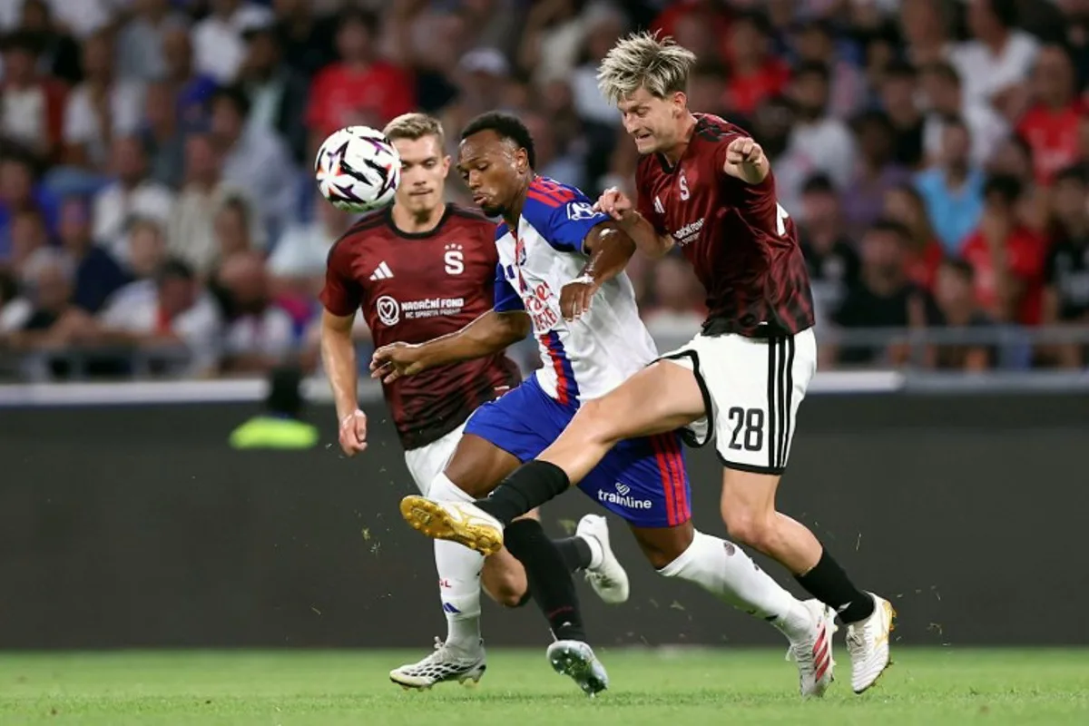 Lyon's Belgian forward #17 LoÏs Openda (C) fights for the ball with Sparta Praha's Czech midfielder #28 Roman Macek (R) during the UEFA Champions League third qualifying round - second leg football match between Olympique Lyonnais (OL) and Sparta Prague at Groupama Stadium in Decines-Charpieu, central-eastern France on August 11, 2026. Alex MARTIN / AFP