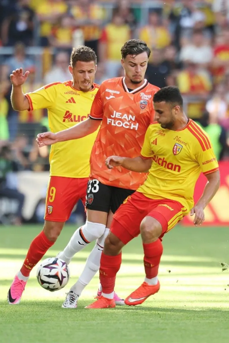 Lens' Belgian midfielder #09 Thorgan Hazard (L) and Lens' Algerian midfielder #08 Yacine Titraoui (R) fight for the ball with Lorient's French midfielder #33 Gabin Bernardeau (C) during the French L1 football match between RC Lens and FC Lorient at the Stade Bollaert-Delelis in Lens, northern France, on September 5, 2026. Francois LO PRESTI / AFP