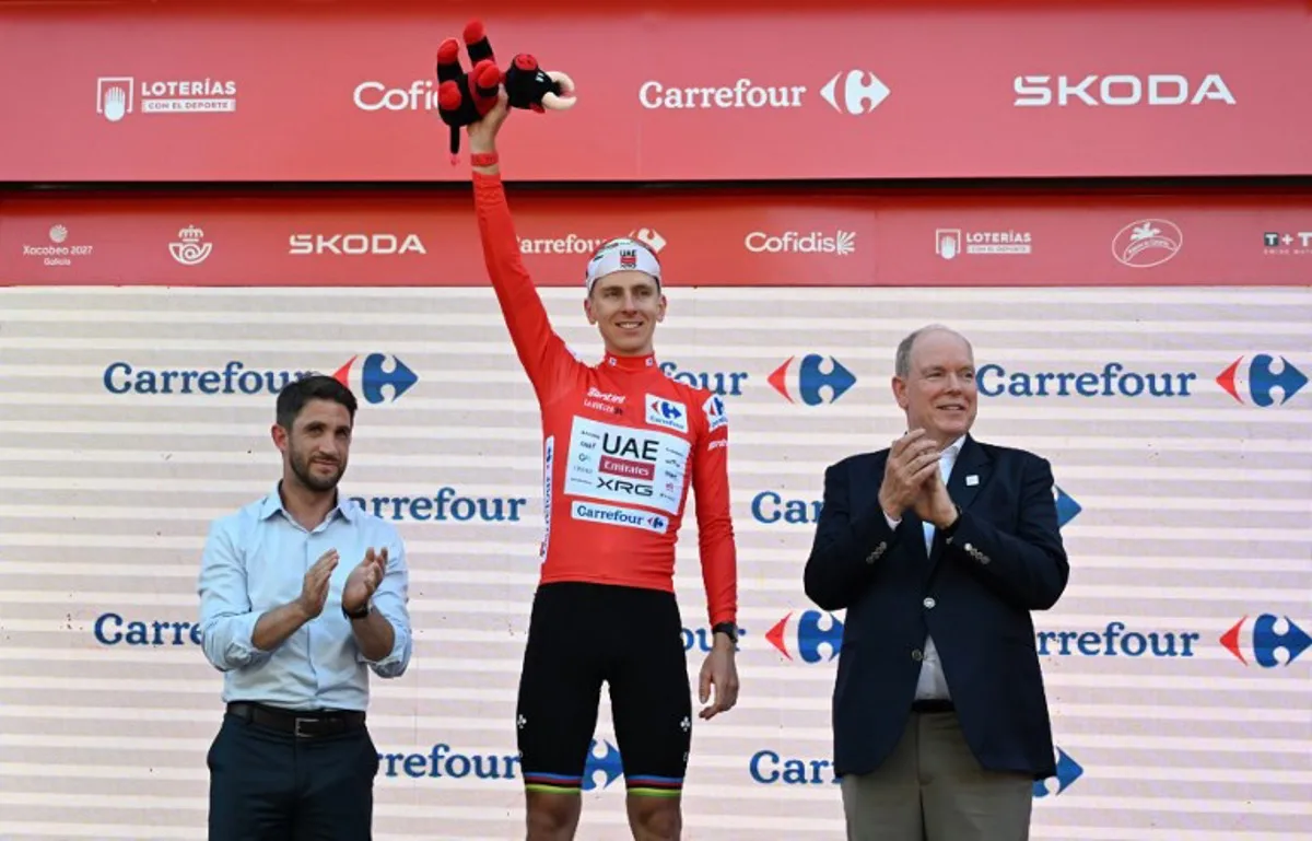 UAE Team Emirates - XRG team's Slovenian rider Tadej Pogacar celebrates on the podium wearing the overall leader's red jersey flanked by Prince's Albert II of Monaco (R) and Manosque's mayor Camille Galtier after the second stage of the Vuelta a Espana 2026, a 214,3 km race between Monaco and Manosque on August 23, 2026.  Miguel MEDINA / AFP