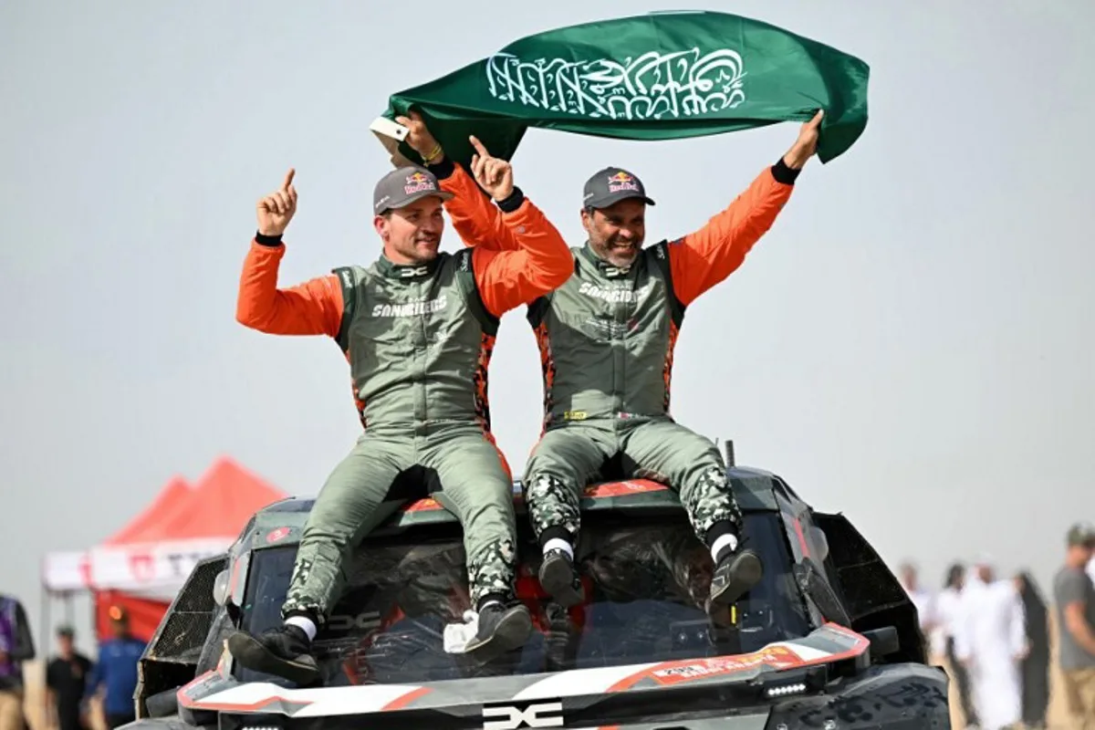 The Dacia Sandriders' Qatari driver Nasser al-Attiyah (R) and Belgian copilot Fabian Lurquin celebrate after winning the 48th edition of the Dakar Rally 2026 in Yanbu, Saudi Arabia, on January 17, 2026. Qatar's Nasser Al-Attiyah secured his sixth Dakar Rally car title in Saudi Arabia. Giuseppe CACACE / AFP