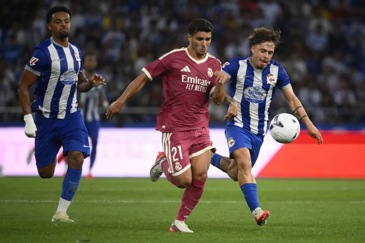 Deportivo La Coruna's Spanish midfielder #21 Mario Soriano Carreno (R) and Real Madrid's Moroccan forward #21 Brahim Diaz (C) vie for the ball during the Teresa Herrera Trophy friendly football match between RC Deportivo de la Coruna and Real Madrid CF at Municipal de Riazor Stadium in A Coruna on August 12, 2026. Miguel RIOPA / AFP