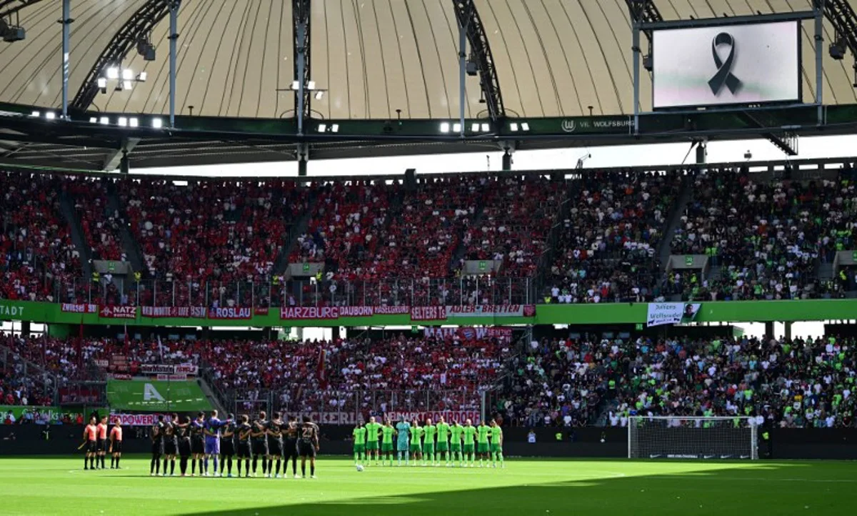 The teams hold a minute of silence for the late former football headcoach Christoph Daum ahead the German first division Bundesliga football match between VfL Wolfsburg and FC Bayern Munich in Wolfsburg, northern Germany, on August 25, 2024.  Tobias SCHWARZ / AFP