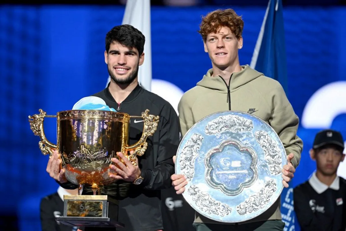 Spain's Carlos Alcaraz (L) celebrates with the trophy after winning the men's singles final against Italy's Jannik Sinner (R) at the China Open tennis tournament in Beijing on October 2, 2024.  Greg Baker / AFP