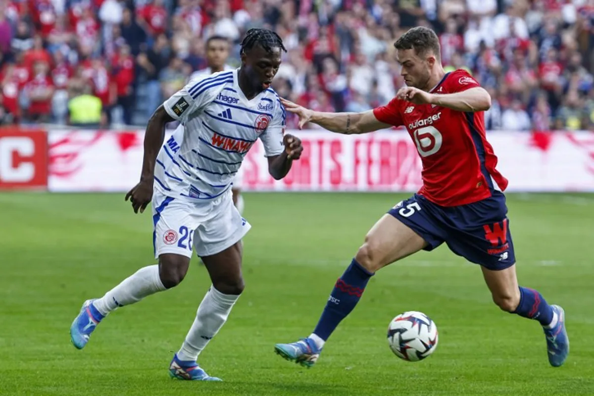 Strasbourg's French forward #26 Dilane Bakwa (L) fights for the ball with Lille's Swedish defender #05 Gabriel Gudmundsson during the French L1 football match between Lille LOSC and RC Strasbourg at Stade Pierre-Mauroy in Villeneuve-d'Ascq, northern France on September 21, 2024.  DENIS CHARLET / AFP