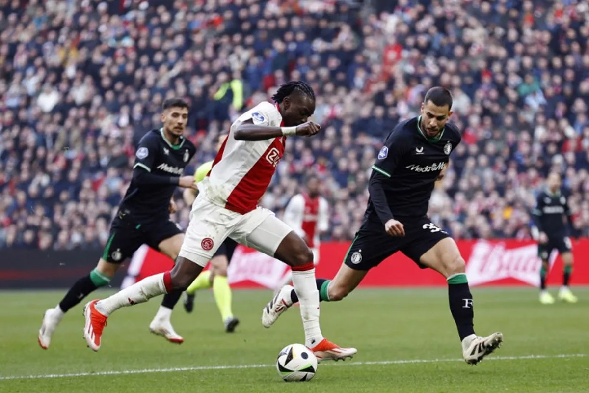 Ajax's Burkinabe forward #20 Bertrand Traore (C) fights for the ball with Feyenoord's Slovakian defender #33 David Hancko (R)  during the Dutch Eredivisie football match between AFC Ajax and Feyenoord at the Johan Cruijff ArenA in Amsterdam, on February 2, 2025.  MAURICE VAN STEEN / ANP / AFP