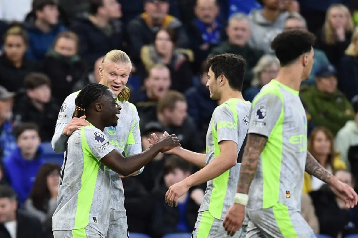 Manchester City's Belgian midfielder #11 Jeremy Doku (L) celebrates with teammates after scoring the opening goal during the English Premier League football match between Everton and Manchester City at Hill Dickinson Stadium in Liverpool on May 4, 2026.  PETER POWELL / AFP