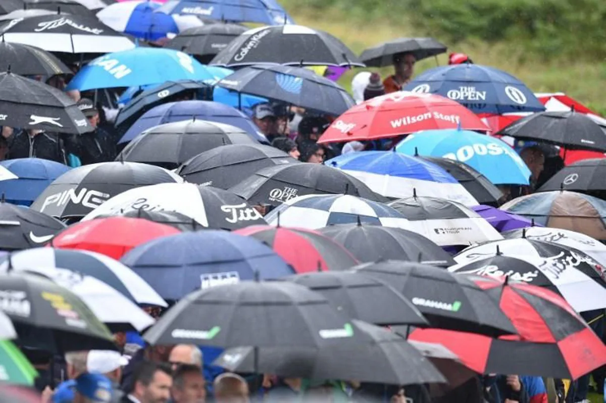 Spectators shelter under umbrellas during the second round of the British Open golf Championships at Royal Portrush golf club in Northern Ireland on July 19, 2019. Glyn KIRK / AFP RESTRICTED TO EDITORIAL USE