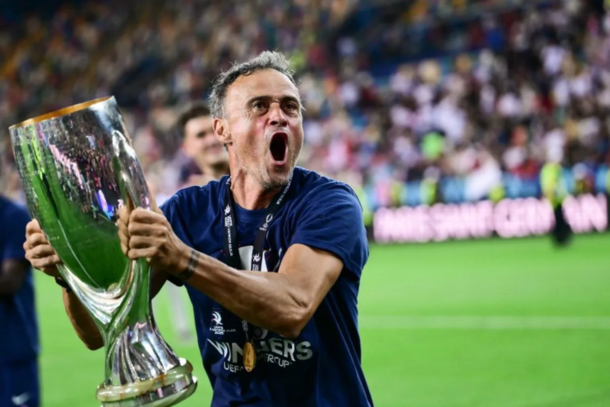 Paris Saint-Germain's Spanish headcoach Luis Enrique celebrates with the trophy after winning the 2025 UEFA Super Cup final football match between Paris Saint-Germain (FRA) and Tottenham Hotspur FC (ENG) at the Friuli stadium, in Udine, on August 13, 2025.  Marco BERTORELLO / AFP