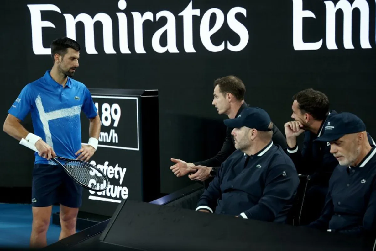 Serbia's Novak Djokovic (L) consults his coach, Andy Murray (Top-C) during the men's singles match against USA's Nishesh Basavareddy on day two of the Australian Open in Melbourne on January 13, 2025.   David GRAY / AFP