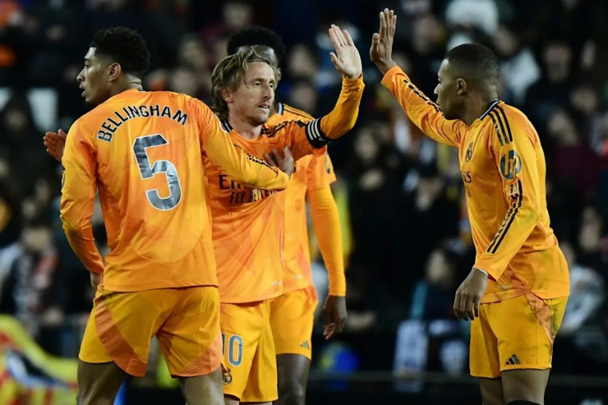 Real Madrid's Croatian midfielder #10 Luka Modric (C) celebrates with teammate Real Madrid's English midfielder #05 Jude Bellingham (L) and Real Madrid's French forward #09 Kylian Mbappe (R) after scoring a goal during the Spanish league football match between Valencia CF and Real Madrid CF at the Mestalla stadium in Valencia on January 3, 2025.  JOSE JORDAN / AFP