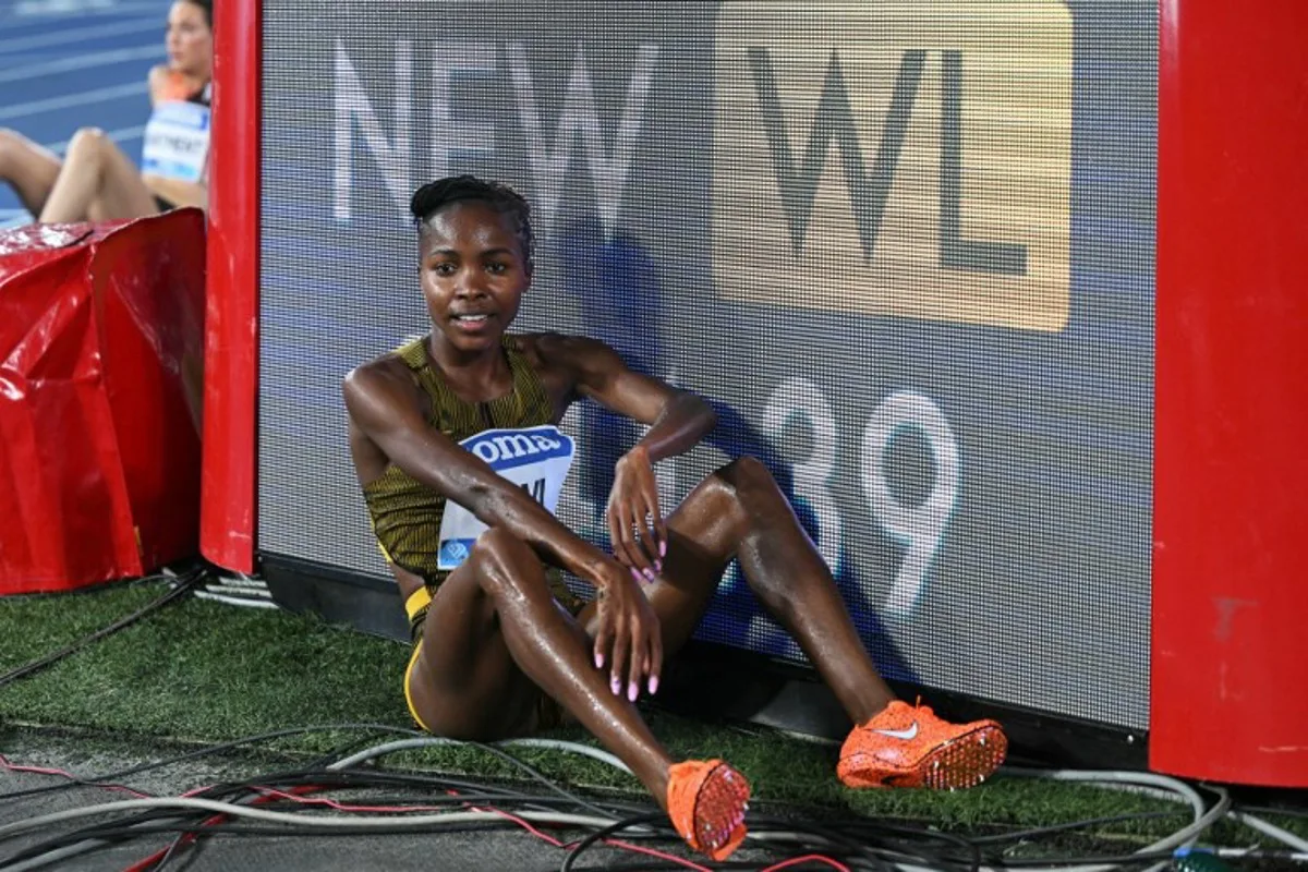Bahrain's Winfred Mutile Yavi rests next to a board displaying her world leading (WL) performance in this season after winning the women's 3000m steeplechase event of the Diamond League athletics meeting at the Olympic stadium in Rome on August 30, 2024. Tiziana FABI / AFP