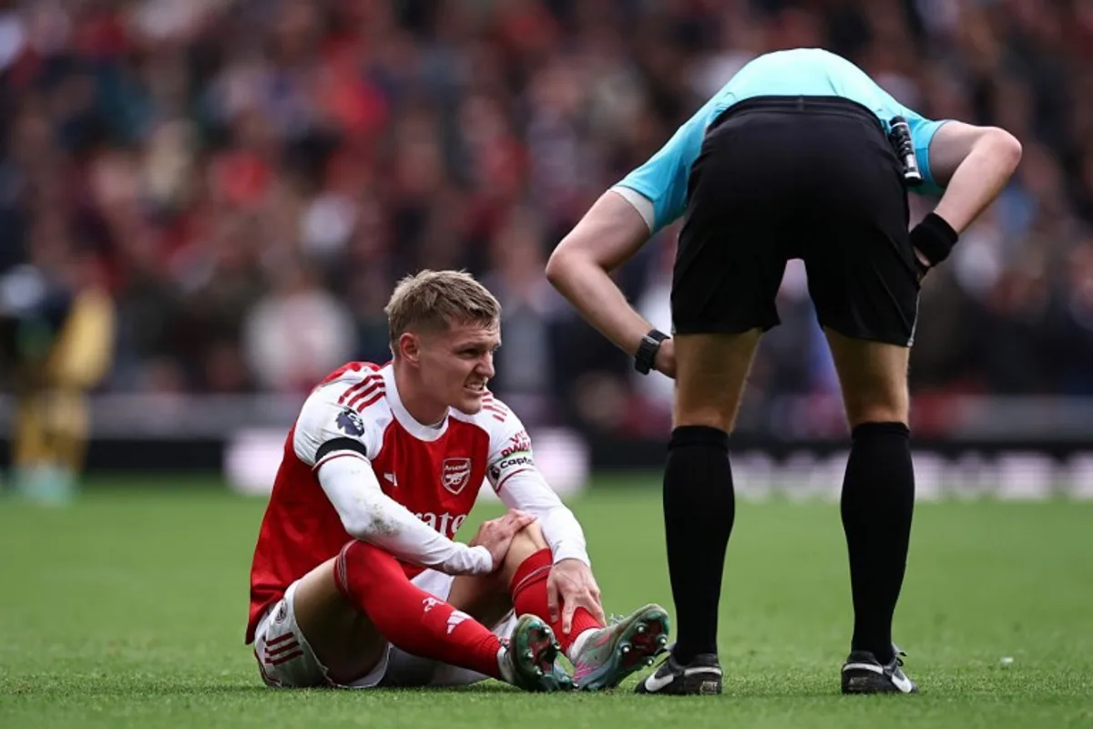 Arsenal's Norwegian midfielder #08 Martin Odegaard (L) reacts after picking up an injury during the English Premier League football match between Arsenal and West Ham United at the Emirates Stadium in London on October 4, 2025. HENRY NICHOLLS / AFP