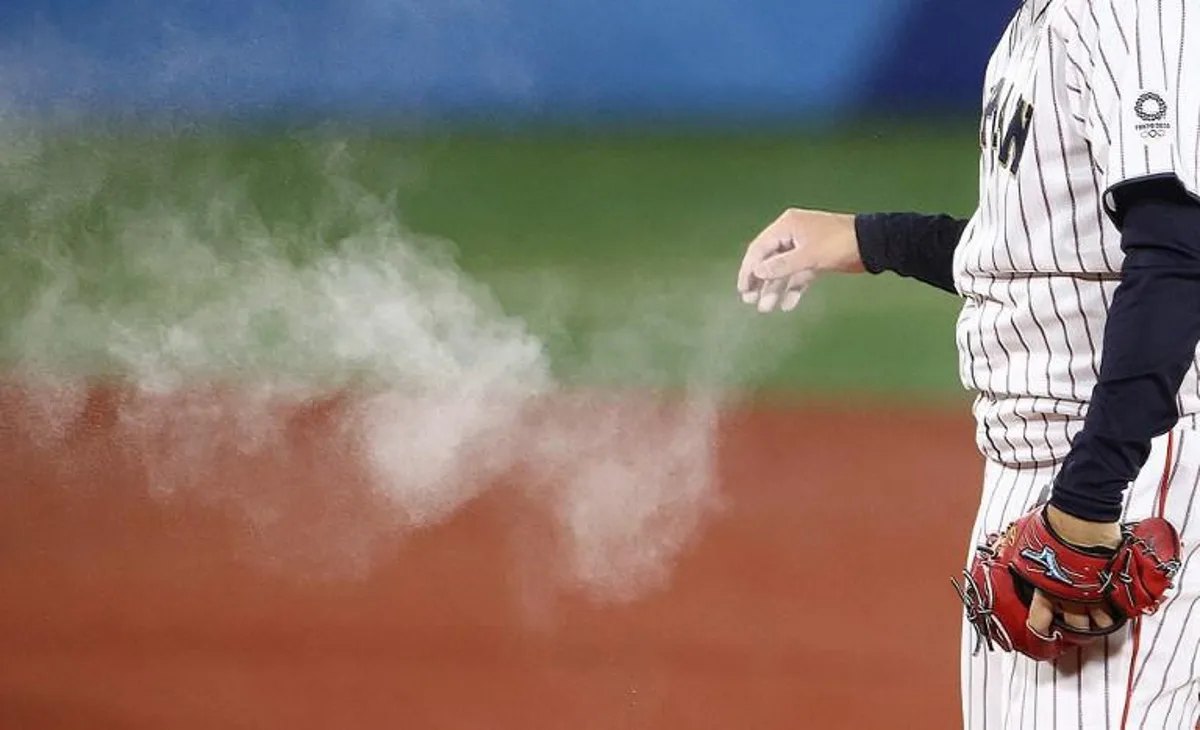 Smokes of rosin powder raises from a hand of Japan's relief pitcher Hiromi Itoh during the seventh inning of the Tokyo 2020 Olympic Games baseball gold medal game between USA and Japan at Yokohama Baseball Stadium in Yokohama, Japan, on August 7, 2021.  KAZUHIRO FUJIHARA / AFP