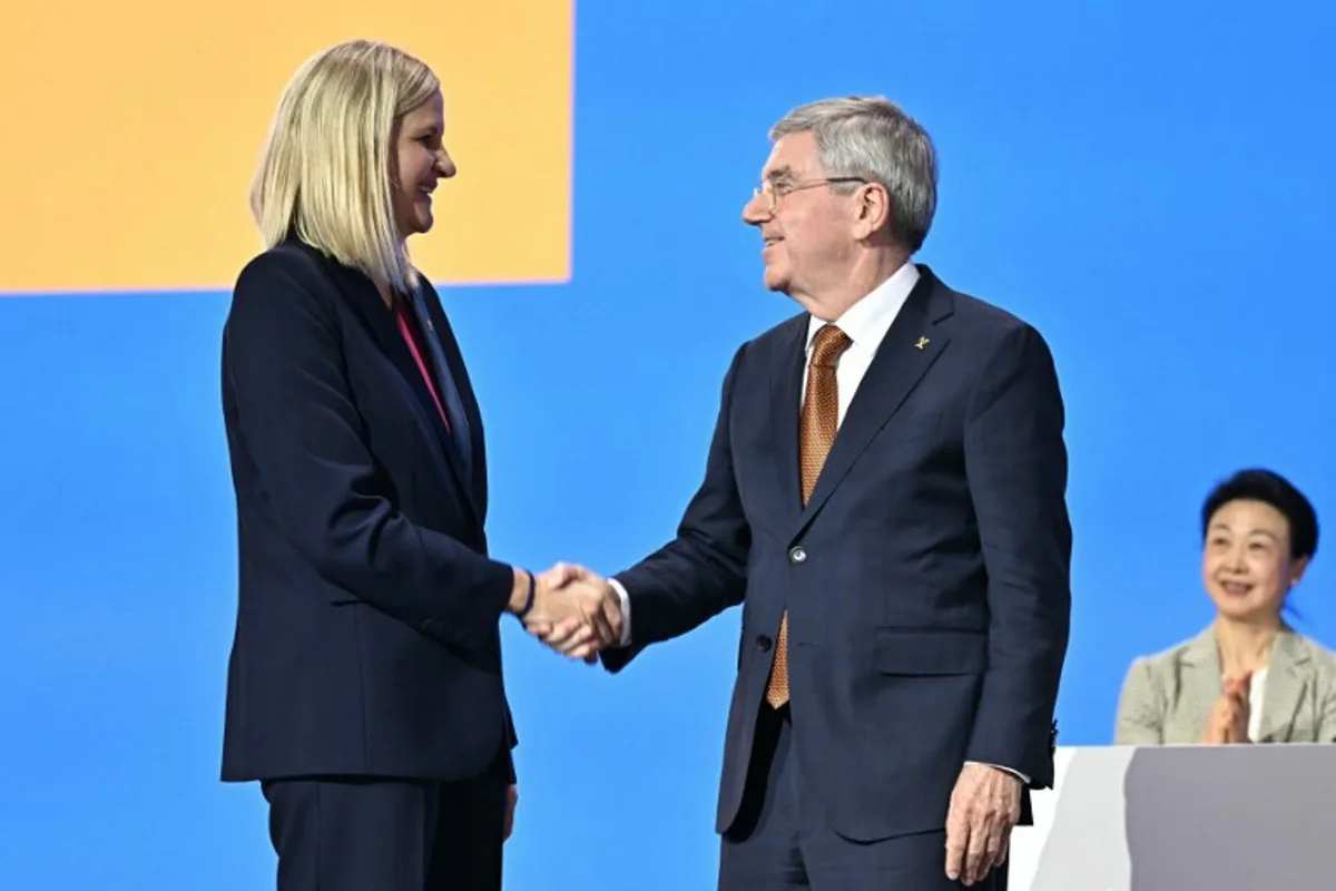 Zimbabwean candidate for the presidency of the International Olympic Committee (IOC) Kirsty Coventry (L) shakes hands with IOC outgoing president Thomas Bach after being elected during the 144th IOC Session on the day of the election of the next President of the International Olympic Committee, in Costa Navarino, Greece on March 20, 2025. Zimbabwe's Kirsty Coventry elected president of International Olympic Committee on March 20, 2025. Fabrice COFFRINI / AFP