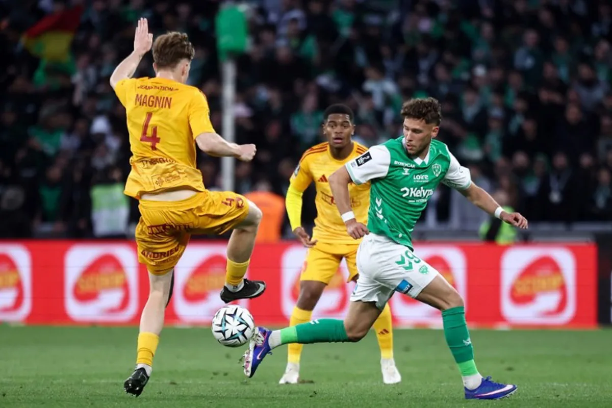 Rodez's Swiss defender #04 Mathis Magnin (L) fights for the ball with Saint-Etienne's Belgian forward #09 Lucas Stassin (R) during the French L1-L2 playoff second leg football match between AS Saint-Etienne and Rodez at the stade Geoffroy Guichard in Saint-Etienne, south-eastern France on May 15, 2026. Alex MARTIN / AFP