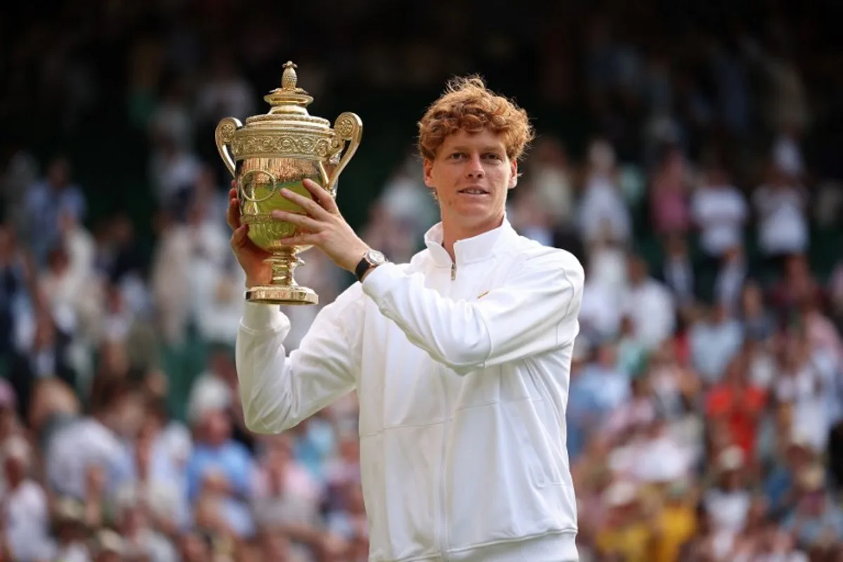 Italy's Jannik Sinner celebrates with the winner's trophy as he poses for pictures following his victory against Spain's Carlos Alcaraz at the end of their men's singles final tennis match on the fourteenth day of the 2025 Wimbledon Championships at The All England Lawn Tennis and Croquet Club in Wimbledon, southwest London, on July 13, 2025. HENRY NICHOLLS / AFP