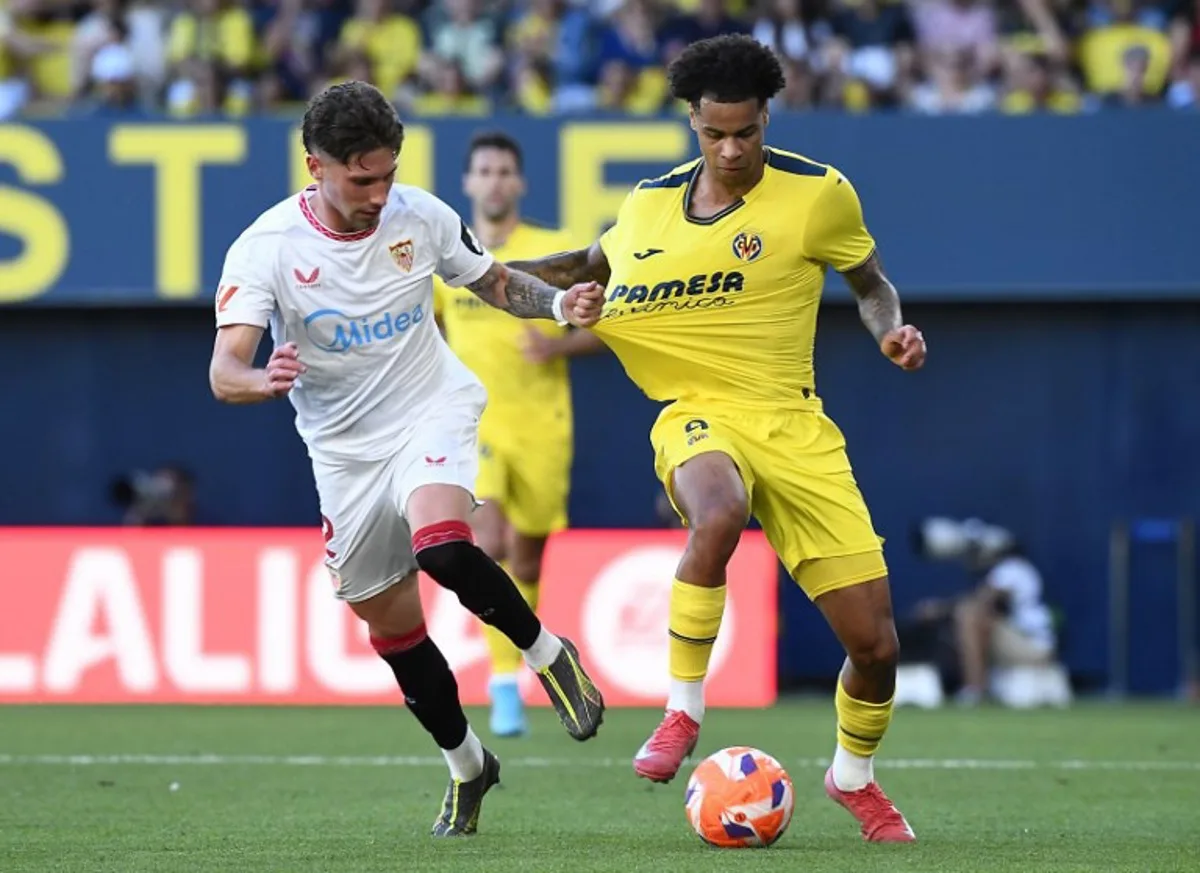 Sevilla's Spanish defender #02 Jose Carmona grasps Villarreal's Canadian midfielder #09 Tajon Buchanan's jersey during the Spanish league football match between Villarreal CF and Sevilla FC at La Ceramica Stadium in Vila-real, on May 25, 2025. Jose Jordan / AFP