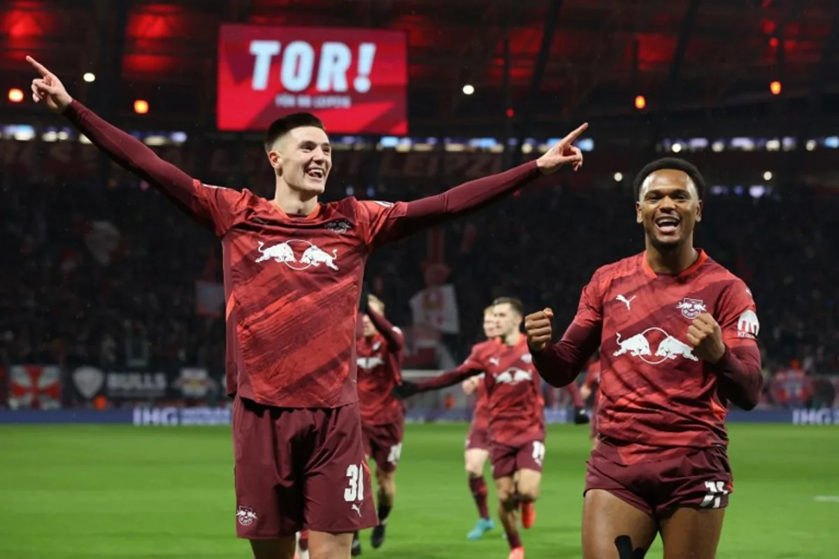 Leipzig's Slovenian forward #30 Benjamin Sesko celebrates scoring his team's first goal with Leipzig's Belgian forward #11 Lois Openda during the German first division Bundesliga football match between RB Leipzig and Eintracht Frankfurt in Leipzig on December 15, 2024.  Ronny HARTMANN / AFP