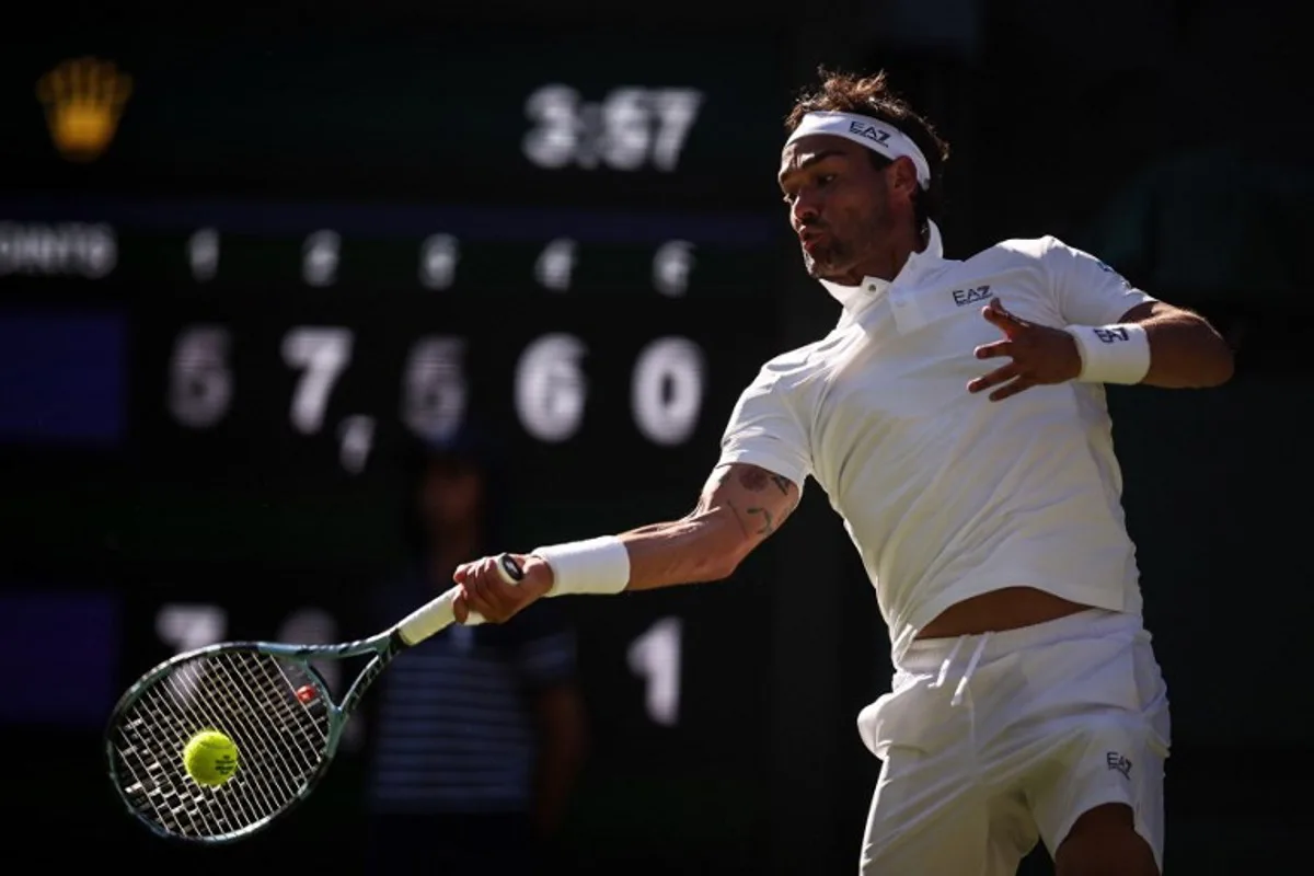 Italy's Fabio Fognini plays a forehand return to Spain's Carlos Alcaraz during their men's singles first round tennis match on the first day of the 2025 Wimbledon Championships at The All England Lawn Tennis and Croquet Club in Wimbledon, southwest London, on June 30, 2025. HENRY NICHOLLS / AFP