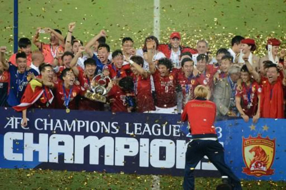 Guangzhou Evergrande football players celebrate with the trophy after winning their AFC League second leg final football game against FC Seoul in Guangzhou on November 9, 2013. The final score was 1 - 1 giving Evergrande victory on away goals.  AFP PHOTO / Ed Jones