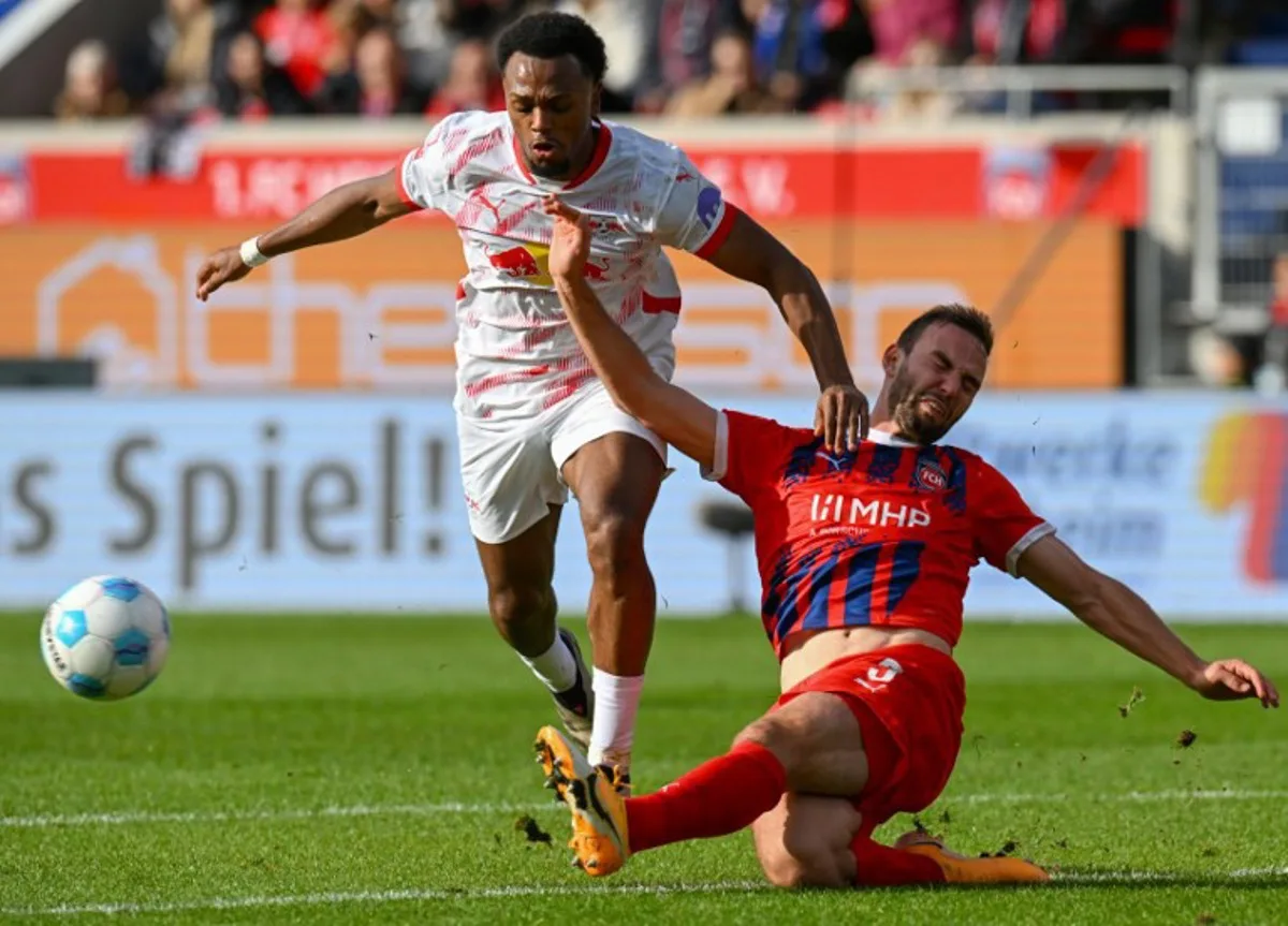 Leipzig's Belgian forward #11 Lois Openda (L) and Heidenheim's German midfielder #05 Benedikt Gimber vie for the ball during the German first division Bundesliga football match between 1 FC Heidenheim and RB Leipzig in Heidenheim, southern Germany on October 6, 2024.  THOMAS KIENZLE / AFP