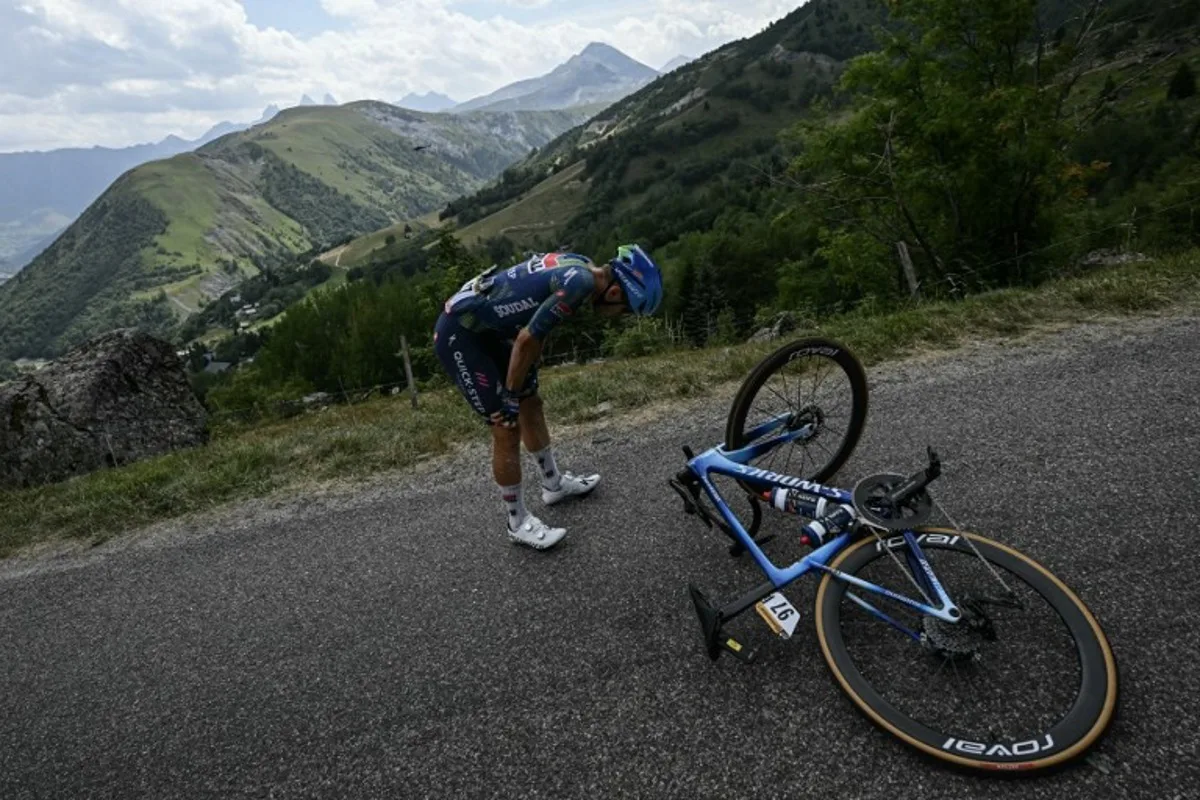 Soudal Quick-Step team's Belgian rider Ilan Van Wilder awaits technical assistance on the roadside during the 20th stage of the 113th edition of the Tour de France cycling race, 170,9 km between Le Bourg-d'Oisans and Alpe d'Huez in the French Alps, on July 25, 2026. Loic VENANCE / AFP